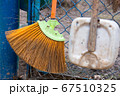 Old broom and dirty scoop near the iron blue mesh fence 67510325