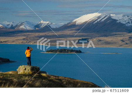 Girl in yellow jacket looking at Lake Tekapo from Mount John observatory, South Island, New Zealand 67511609