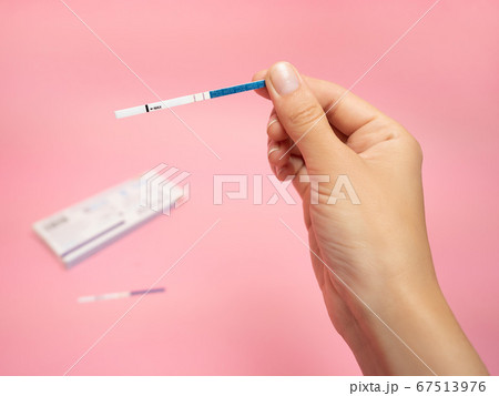 Female hand holding positive pregnancy test isolated on pink background. The abbreviation HCG on the blue bar means Human chorionic gonadotropin is a hormone produced by cells that are surrounding a 67513976