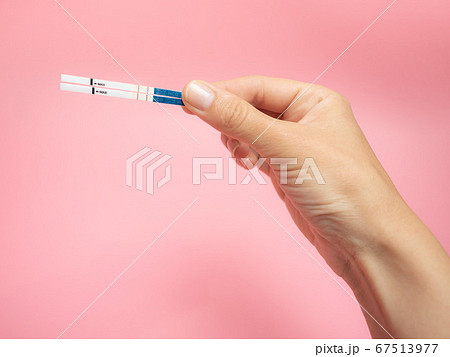 Female hand holding positive pregnancy test isolated on pink background. The abbreviation HCG on the blue bar means Human chorionic gonadotropin is a hormone produced by cells that are surrounding a 67513977