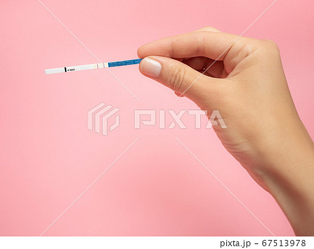 Female hand holding positive pregnancy test isolated on pink background. The abbreviation HCG on the blue bar means Human chorionic gonadotropin is a hormone produced by cells that are surrounding a 67513978