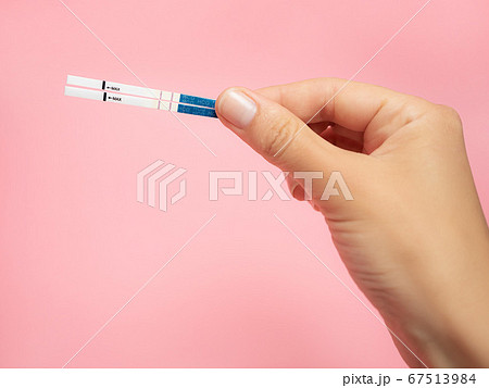 Female hand holding positive pregnancy test isolated on pink background. The abbreviation HCG on the blue bar means Human chorionic gonadotropin is a hormone produced by cells that are surrounding a Female hand holding positive pregnancy test isolated on pink background. The abbreviation HCG on the blue bar means Human chorionic gonadotropin is a hormone produced by cells that are surrounding a 67513984