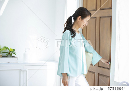 玄関扉を開ける女性 67516044