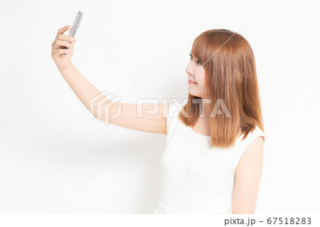 スマホで自撮りするワンピースを着た女性 67518283