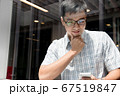 Handsome asian boy smiling and checking his smartphone in the hallway.  67519847