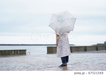 雨の中海辺で佇む女性の写真素材