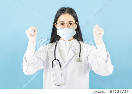 Smart young asian woman doctor in lab coat with Medical face mask,white latex medical gloves and stethoscope against blue background,health care concept 67522737