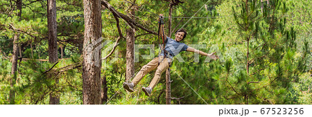 Young attractive man in adventure rope park in safety equipment BANNER, LONG FORMAT Young attractive man in adventure rope park in safety equipment BANNER, LONG FORMAT 67523256