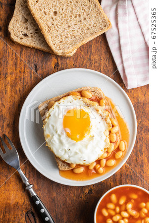 Toast with fried egg and baked beans. Toast with fried egg and baked beans. 67525365