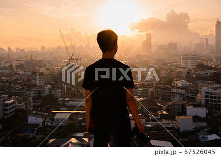 Young asian man with camera standing on top of 67526045