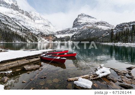 Red canoes parked in snowy valley at wooden pier. 67526144