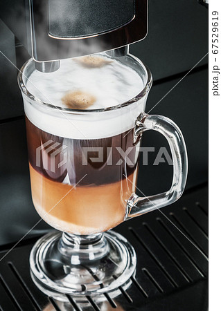 cup with hot cappuccino with foam prepared in the coffee machine 67529619