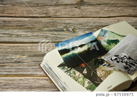 Photo album and strewn colorful various photographs on a wooden table Photo album and strewn colorful various photographs on a wooden table 67530975