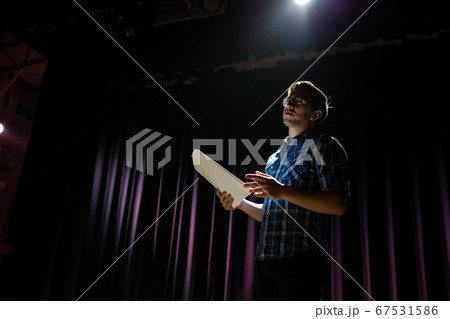Stand up comedian on stage. Young man talks joke into microphone or sings songs. Stand up comedian on stage. Young man talks joke into microphone or sings songs. 67531586