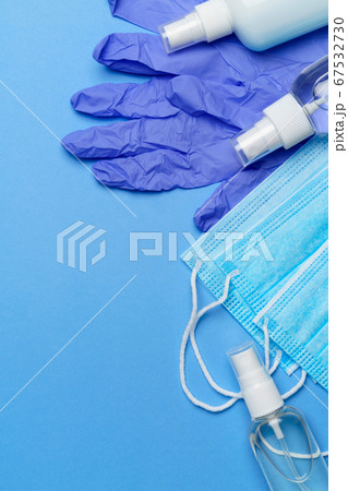 bottle of lotion, sanitizer or liquid soap, latex rubber gloves, hat and protective mask over blue background - flat layout 67532730