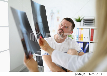 Man in medical office is looking at x-rays with doctor. Man in medical office is looking at x-rays with doctor. 67534516