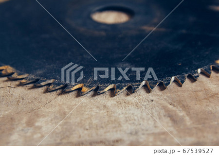 Close-up blade circular saw on the background of the wooden table. Workshop for the production of wooden products. Joiner's cutting tool. Backdrop with free copy space. Top view Close-up blade circular saw on the background of the wooden table. Workshop for the production of wooden products. Joiner's cutting tool. Backdrop with free copy space. Top view 67539527