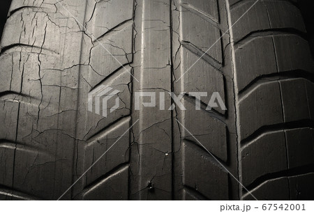 Old damaged, worn black tire tread, large cracks in the car wheel. Old damaged, worn black tire tread, large cracks in the car wheel. 67542001
