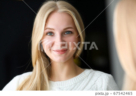 Smiling beautiful blonde woman looking in mirror Smiling beautiful blonde woman looking in mirror 67542465