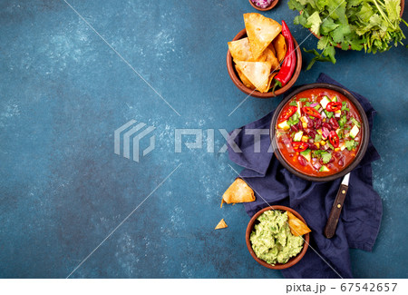 Mexican black bean soup with tomato, avocado and totopos. Blue background, top view Mexican black bean soup with tomato, avocado and totopos. Blue background, top view 67542657