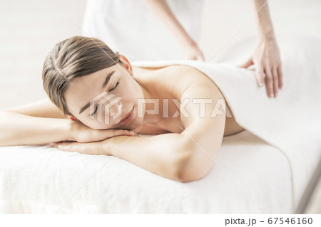 明るい雰囲気のエステサロンでマッサージを受ける若い女性の写真素材