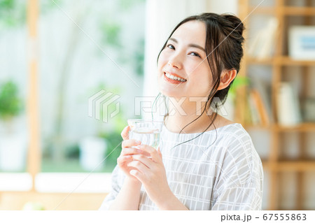 リビングでミネラルウォーターを飲む若い女性 リビングでミネラルウォーターを飲む若い女性 67555863