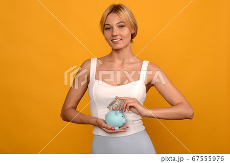 woman hand putting 100 dollars into piggy for 67555976