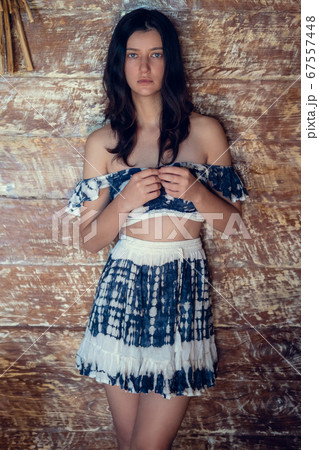 Young pretty woman wearing stylish summer outfit, standing over wooden rustic vintage wall in eco house or bungalow. Tropical vacation and summer fashion Young pretty woman wearing stylish summer outfit, standing over wooden rustic vintage wall in eco house or bungalow. Tropical vacation and summer fashion 67557448