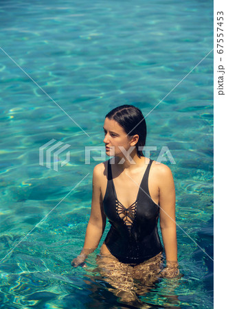 Young beautiful woman in black bikini in the pool during hot sunny summer day. Tropical vacation 67557453