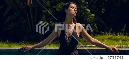 Young beautiful woman in black bikini in the pool during hot sunny summer day. Tropical vacation 67557454