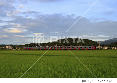 糸島市の田園地帯を行く筑肥線303系 67559371