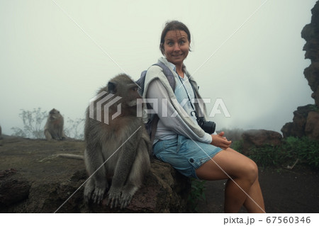 Caucasian woman in a shorts sitting near monkey. 67560346