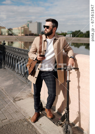 Young man in elegant stylish casualwear and sunglasses standing by riverside Young man in elegant stylish casualwear and sunglasses standing by riverside 67561847