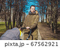 beautiful and young woman mother and baby in a stroller walking in the park 67562921