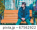 Middle-aged man resting in a garden on a wooden bench enjoying life and weather. 67562922