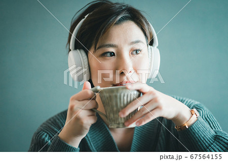 ワイヤレスヘッドホンで音楽を聴く30代女性の写真素材