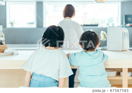 家の中で子供二人が並んで母親の背中を見ている 朝食　食卓　シングルマザー 67567583
