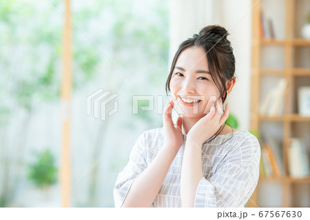 リビングで肌のハリを実感する若い女性 67567630