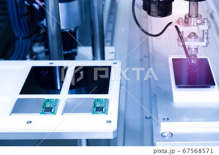 automatic robot arm with vacuum sucker working in the production line and assembling smartphone screens in the new innovative and high technology smartphone factory. . 67568571