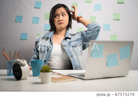 Asian woman feel confused working on a laptop and Asian woman feel confused working on a laptop and 67573270