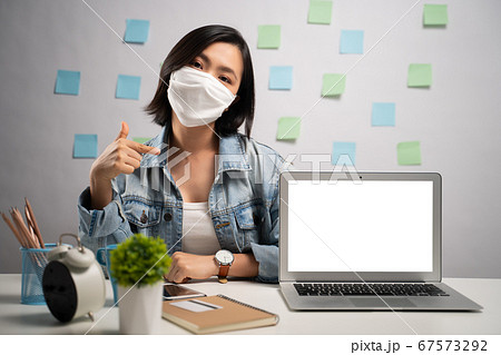 Asian woman wearing protective face mask showing 67573292
