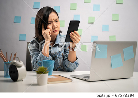Asian woman looking at smart phone reading news 67573294