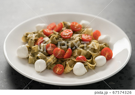 fettuccine with pesto, tomatoes and mozzarella on white plate 67574326