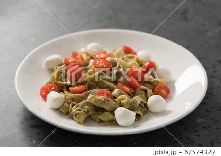 fettuccine with pesto, tomatoes and mozzarella on white plate 67574327