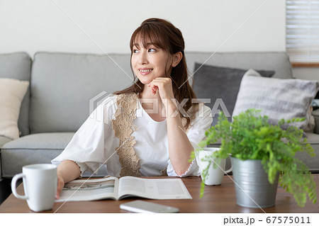 リビングでお茶を飲みながら雑誌を読む若い女性 リビングでお茶を飲みながら雑誌を読む若い女性 67575011
