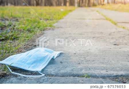 a medical mask lies on a footpath against the background of a city Park 67576053