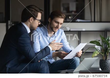 Caucasian businessmen discuss financial paperwork at meeting Caucasian businessmen discuss financial paperwork at meeting 67580734