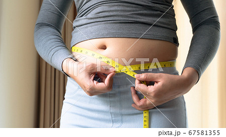 Fat woman hand holding measurement tape on her belly fat. woman diet lifestyle and build muscle Fat woman hand holding measurement tape on her belly fat. woman diet lifestyle and build muscle 67581355