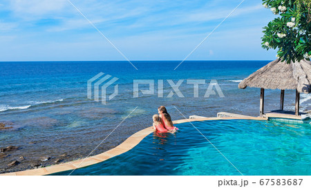 Mother with child in infinity swimming pool with 67583687