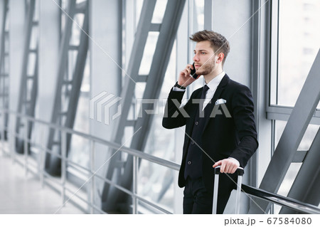 Serious business man talking on smartphone in airport 67584080